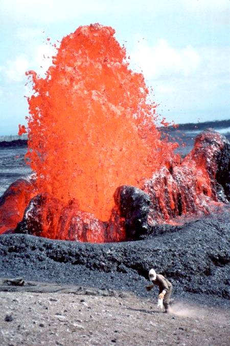 An eruptive situation___this shot taken in 1993 at Kilaue volcano in Hawaii. We can see a geologist collecting spatter samples while fountain erupts.