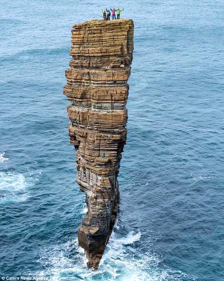 Daredevil climbers pick their way up perilous stack of rocks